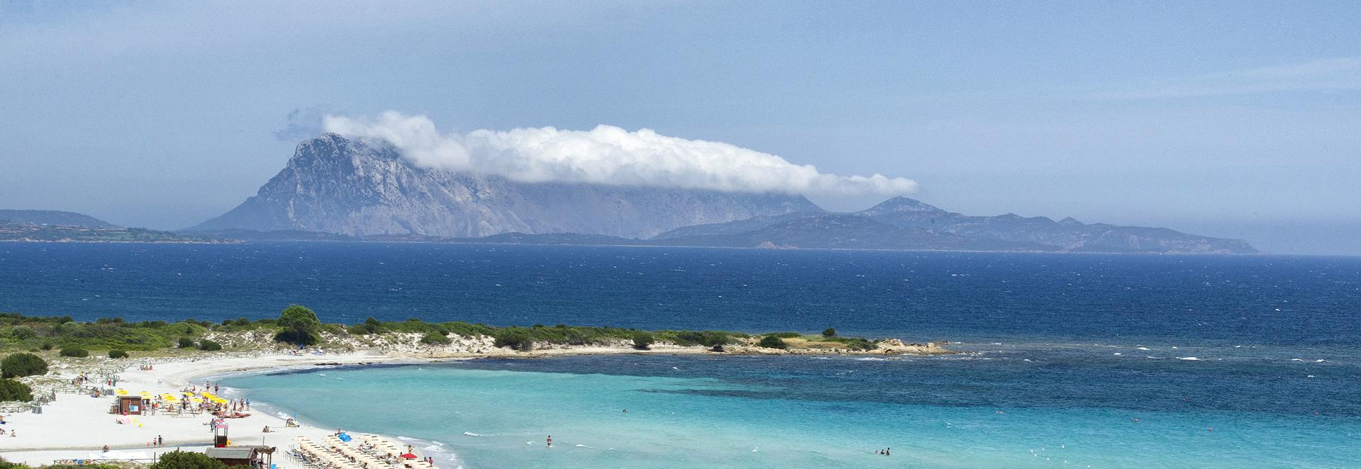 Traghetto bianco naviga in mare blu con montagne sullo sfondo.